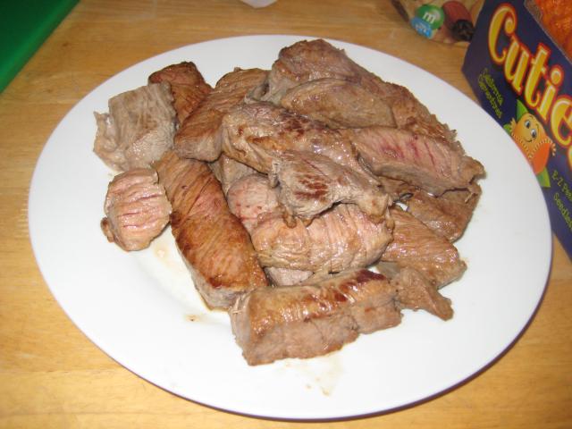 Lots of chunks of cooked steak on a plate.